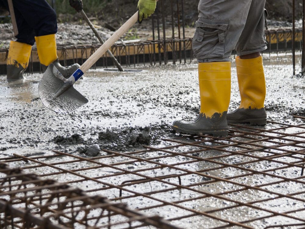 two bricklayers at work on a construction site during the laying of concrete to build the foundations of a house